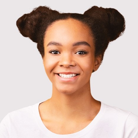Mujer joven con peinado de doble moño, sonrisa brillante, fondo gris claro.